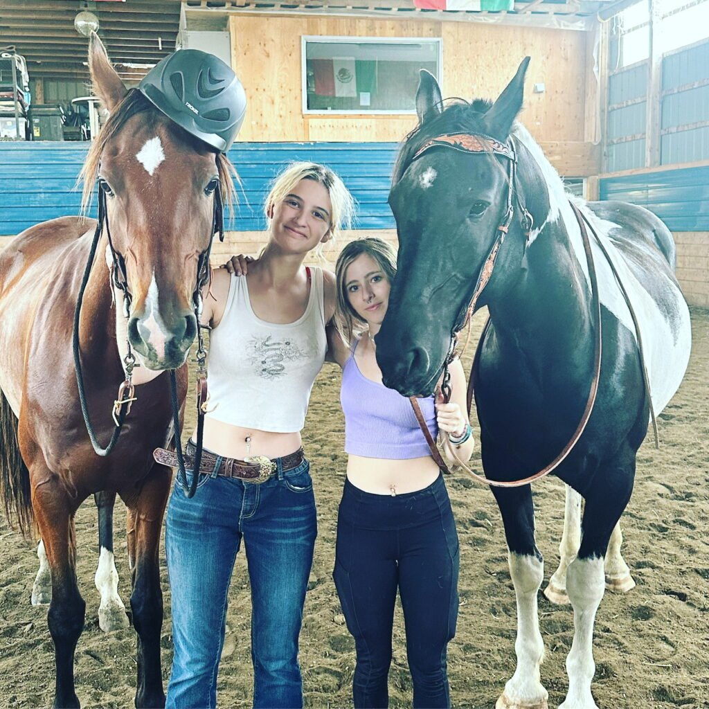 Two sisters standing with their horses, Apollo and Finn